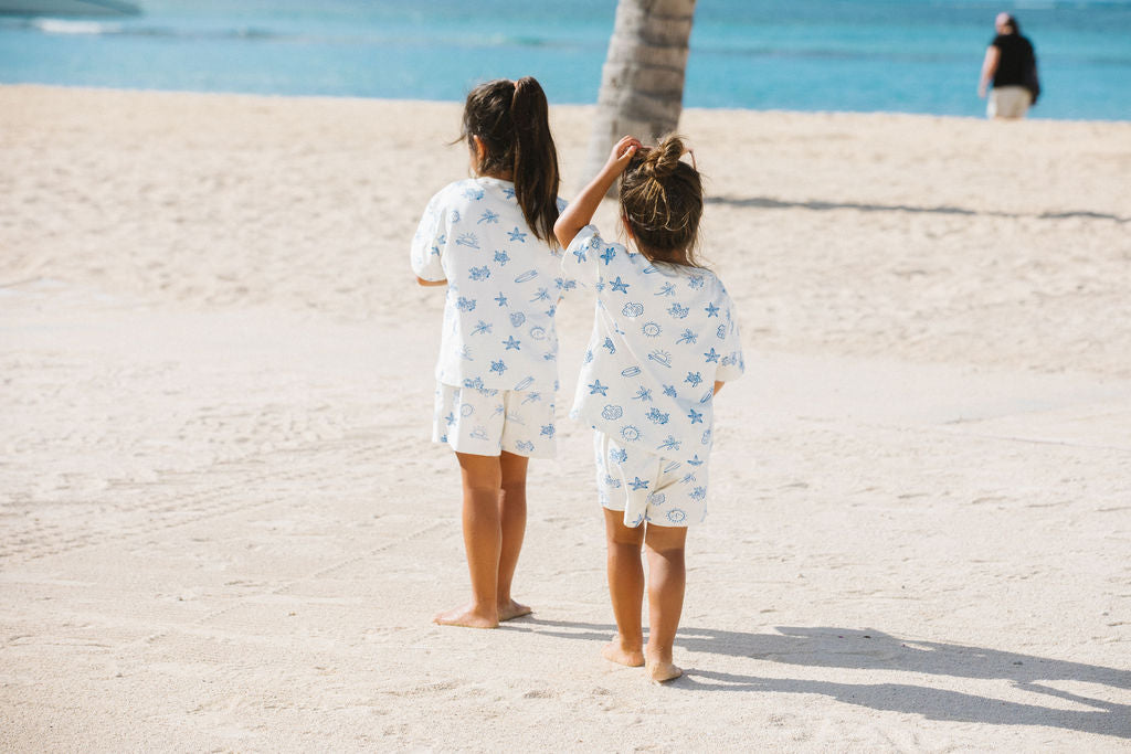 Two children in matching sets walking on the beach